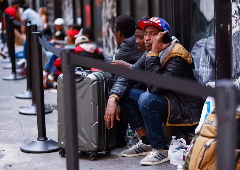 Migrants wait outside the Roosevelt Hotel in midtown Manhattan, New York City, on July 31, 2023. Many newly arrived migrants have been waiting outside the Roosevelt Hotel, which has been turned into a migrant reception center, to try to secure temporary housing. (Photo by KENA BETANCUR / AFP)