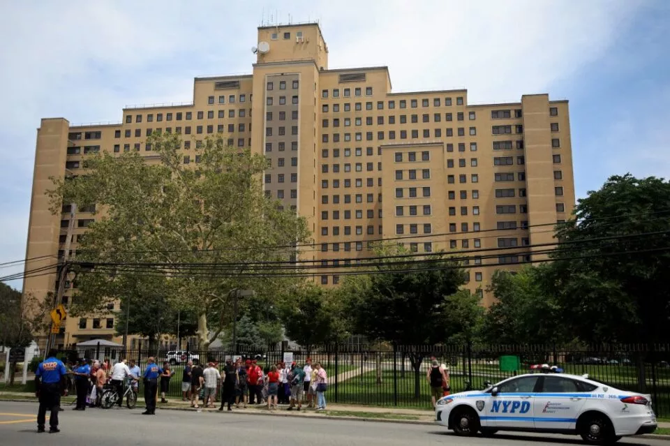 Protesters rally in opposition to the proposed asylum seeker tent shelter on the campus of the state-owned Creedmoor Psychiatric Center (rear) in the Queens borough of New York City on July 29, 2023. (Photo by Leonardo Munoz / AFP)